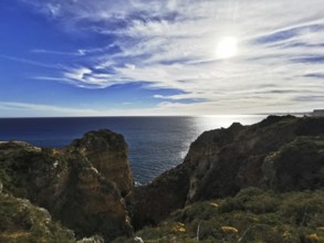 Sun rays illuminate the cliffs and the horizon over the sea, Lagos, Algarve, Portugal