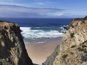 Narrow view of the beach between two rocky cliffs with blue sea and slightly cloudy sky, hiking on