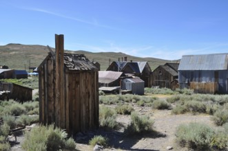 An abandoned village with several wooden houses, toilet, outhouse in the foreground, in a natural,
