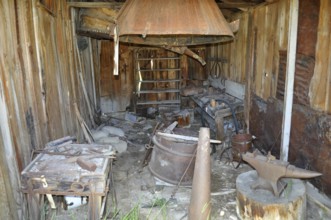 An old blacksmith workshop with rusty tools and wooden structures in an abandoned state, Bodie