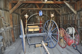 Antique tools and wagons in an old, abandoned wooden barn, fire engines, Bodie Ghost Town,