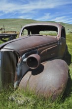 Front view of abandoned rusty car wreck, Chevrolet Coupé, under blue sky, Bodie Ghost Town,