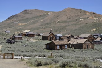 Abandoned wooden houses in a ghost town with desert landscape in the background, Bodie Ghost Town,