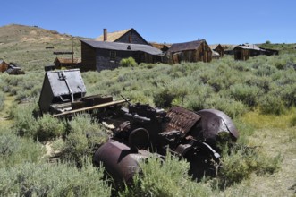 Abandoned wooden houses in mountainous area with rusty car wreck, Bodie Ghost Town, California, USA