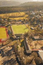 Residential area with sports ground and lots of trees in sunlight taken from the air, Wimberg,