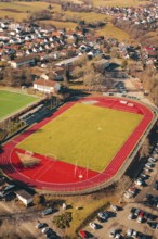 Sports field with red track and surrounding urban area seen from the air, Wimberg, Calw, Germany