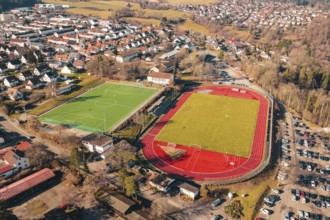 Two sports fields next to each other in a village, shot from the air, with running track and soccer