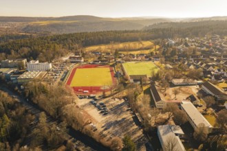 Comprehensive view of the city and surrounding area with sports fields and forest from the air,