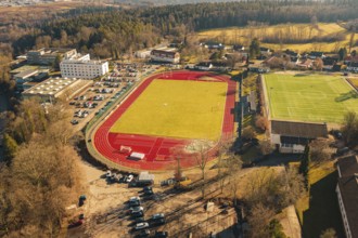 View of sports field with red track surrounded by trees and buildings, Wimberg, Calw, Germany