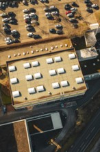 Aerial view of a parking lot and roof of a sports hall in sunshine in a winter environment,