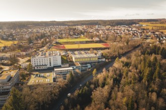 Extensive view of an urban landscape with schools, sports facilities and surrounding forests in a