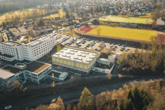Aerial view of a city with buildings, sports ground and parking lot in sunny landscape, Wimberg,