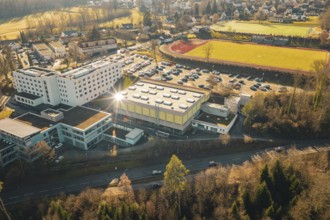 Picture of a school complex with a sports hall, parking lot and a sports field in a wintry
