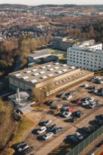Industrial area with large buildings and lots of parked cars, wintry atmosphere, view of the city,