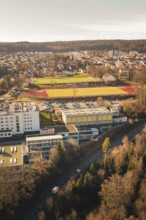 View of a school complex with sports field and playing fields, surrounded by urban landscape and