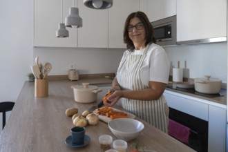 Woman preparing carrots, potatoes and onion for homemade soup in modern kitchen. Comfort food,