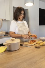 Vertical composition of woman preparing fresh vegetables on kitchen counter. Cozy domestic