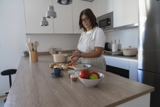 Woman peeling carrots and preparing vegetables for healthy homemade meal in modern kitchen. Clean