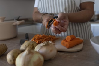 Hands peeling fresh carrot for homemade healthy meal. Clean eating, simple cooking and everyday