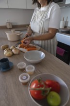 Vertical close up of hands peeling fresh carrot on cutting board in modern kitchen. Healthy