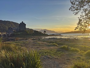 Castle in picturesque landscape at sunset with water and mountains, Highlander, film location,