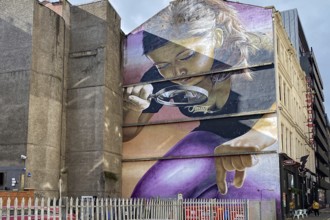 Large wall painting of a woman with magnifying glass in an urban setting, mural, street art,