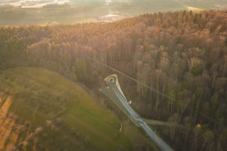 Aerial view of a wooded landscape with a winding road at sunset