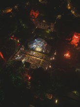 Aerial view of an open-air concert at night with illuminated spectators