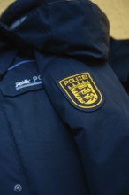 Close-up of a police jacket with a prominent badge on the sleeve