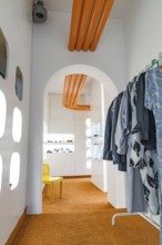 Modern interior with orange accents and a view of other rooms through an arch