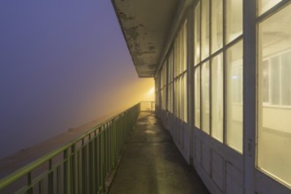 View along a long balcony of Steubenhöft at night in fog, Cuxhaven, Lower Saxony, Germany