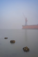 View of old weathered wooden pegs on a dry dock at the port of America on which a crane stands in