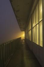 View along a long balcony of Steubenhöft at night in fog, Cuxhaven, Lower Saxony, Germany