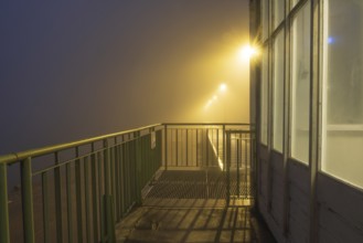 View along a balcony of Steubenhöft at night in fog, Cuxhaven, Lower Saxony, Germany