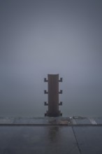 View of a bollard on the quay in fog, Cuxhaven, Lower Saxony, Germany