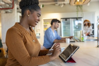 Young professional woman smiling while using a digital tablet and stylus, collaborating with