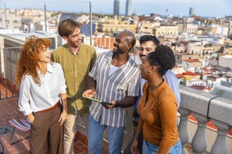 Diverse group of young professionals smiling and laughing on a barcelona rooftop, engaging in a