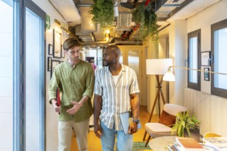 Two diverse colleagues walking and engaging in conversation while collaborating in a modern