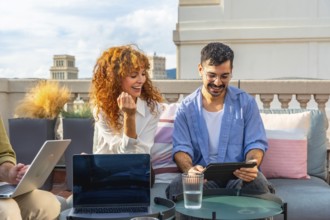 Young business colleagues working together on laptops and tablets, sharing ideas, and enjoying a