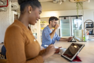Coworkers are enjoying a coffee break in a modern co working space, using tablets for work or
