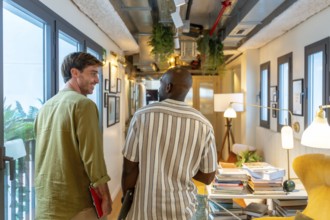 Two diverse colleagues walking and conversing in a modern office or coworking space, sharing ideas