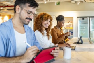 Group of diverse business professionals using digital devices and interacting during a break in a
