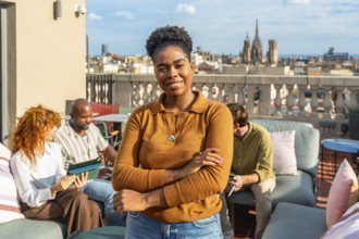 Young black woman with an afro hairstyle smiles at the camera on a modern rooftop terrace while
