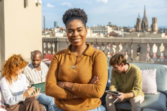 Confident black woman leader standing with arms crossed, smiling at the camera while her diverse