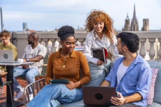 Diverse business professionals collaborating and networking on a barcelona rooftop terrace, using