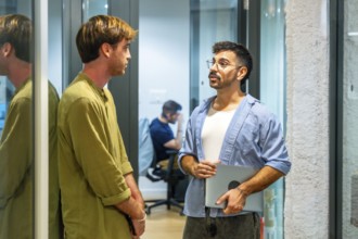 Two male colleagues engaging in an informal discussion during a break in a modern coworking space,