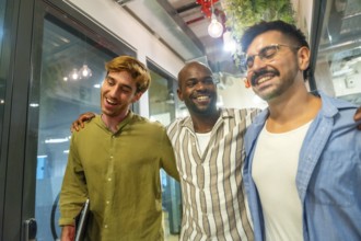 Multi ethnic male colleagues walking and laughing in a modern coworking space, sharing a friendly