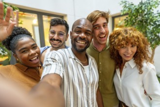 Group of happy diverse business colleagues smiling and looking at camera while taking a selfie