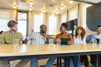 Diverse group of business colleagues sitting at a table during a break or meeting, discussing work