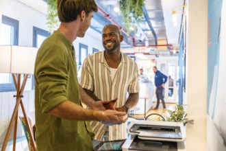 Two diverse male colleagues having a friendly discussion and smiling during a relaxed break in a
